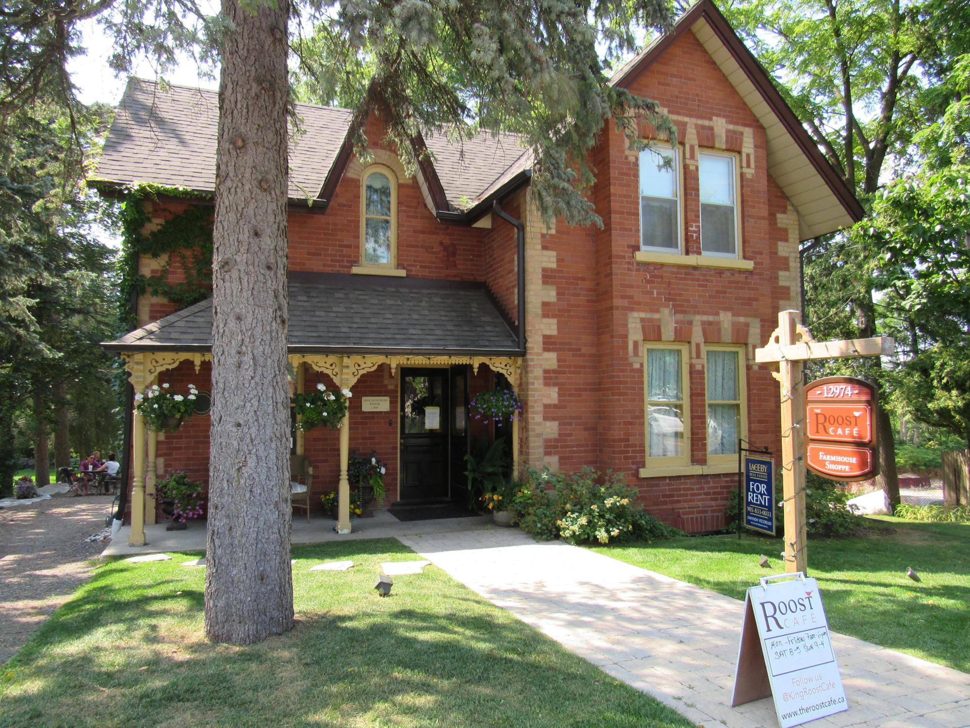 image of The Roost Cafe in King City - a red brick building with a large tree in the front yard 