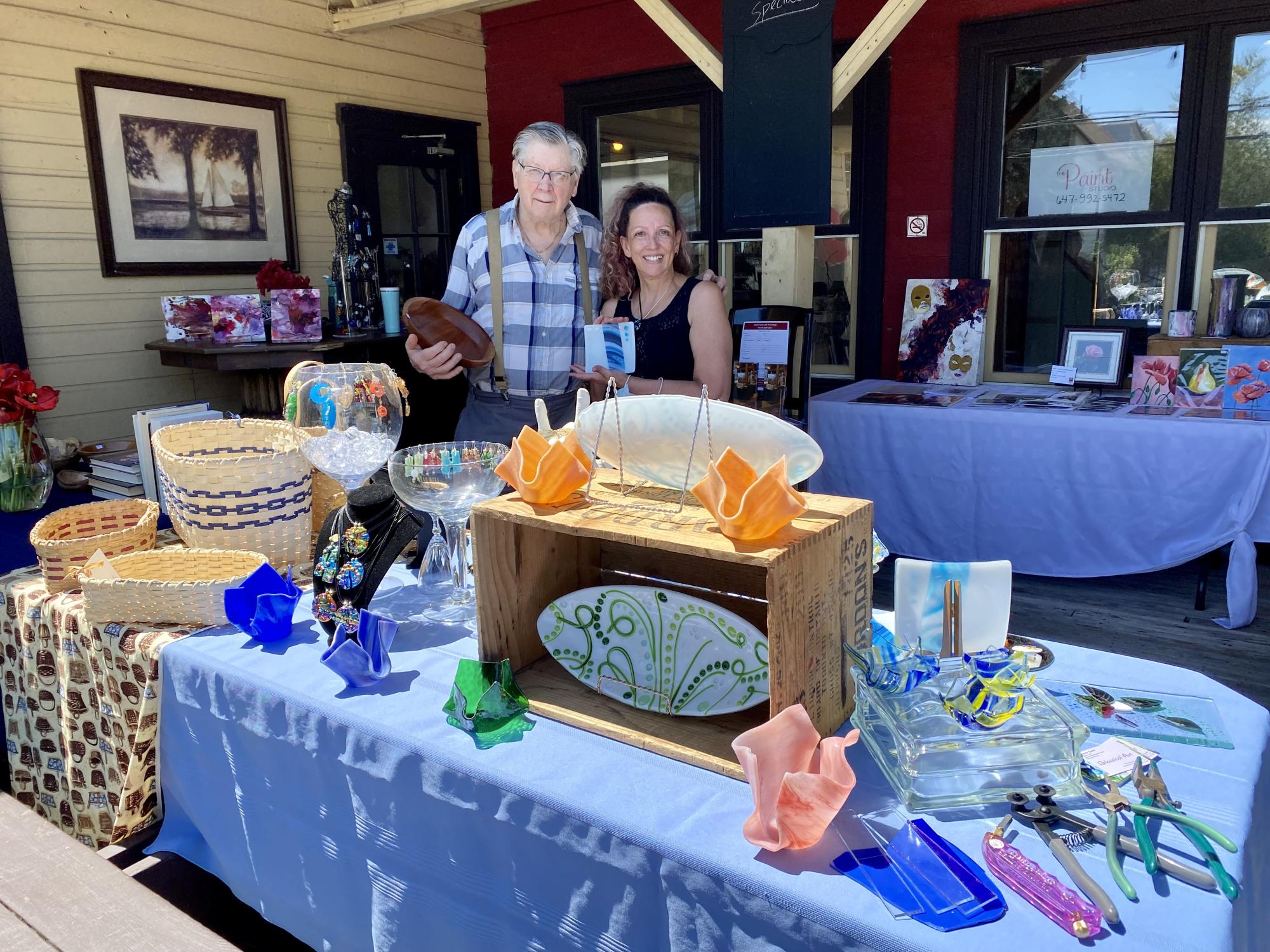Artists from the Olde Mill Art Gallery and Shoppe standing behind a table filled with art for sale
