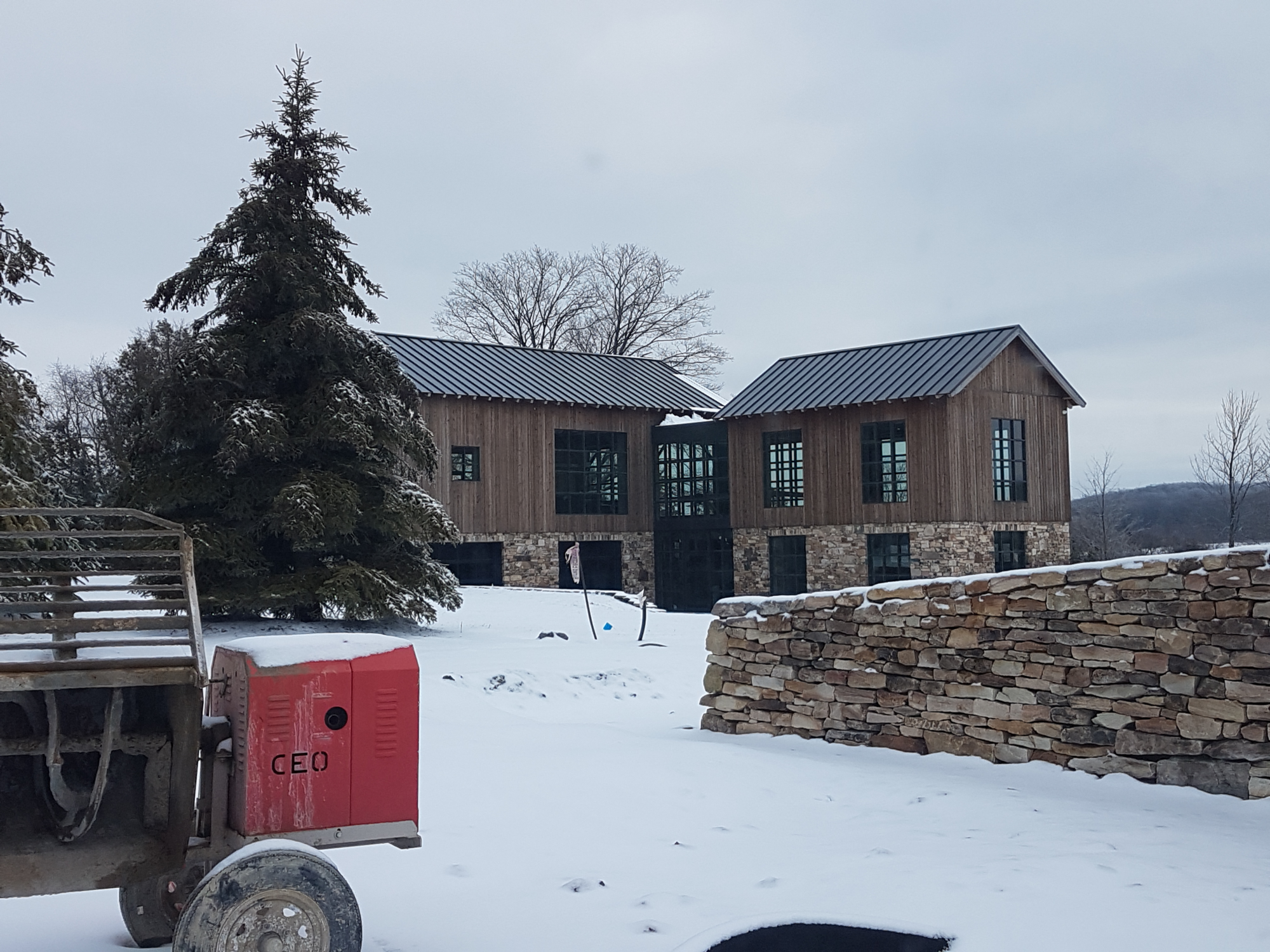photo of the exterior of holland marsh wineries in winter with snow on the ground, a vintage piece of farm equipment, and the building in the background