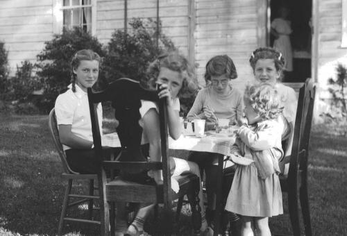 black and white picture of girls sitting at a table outdoors