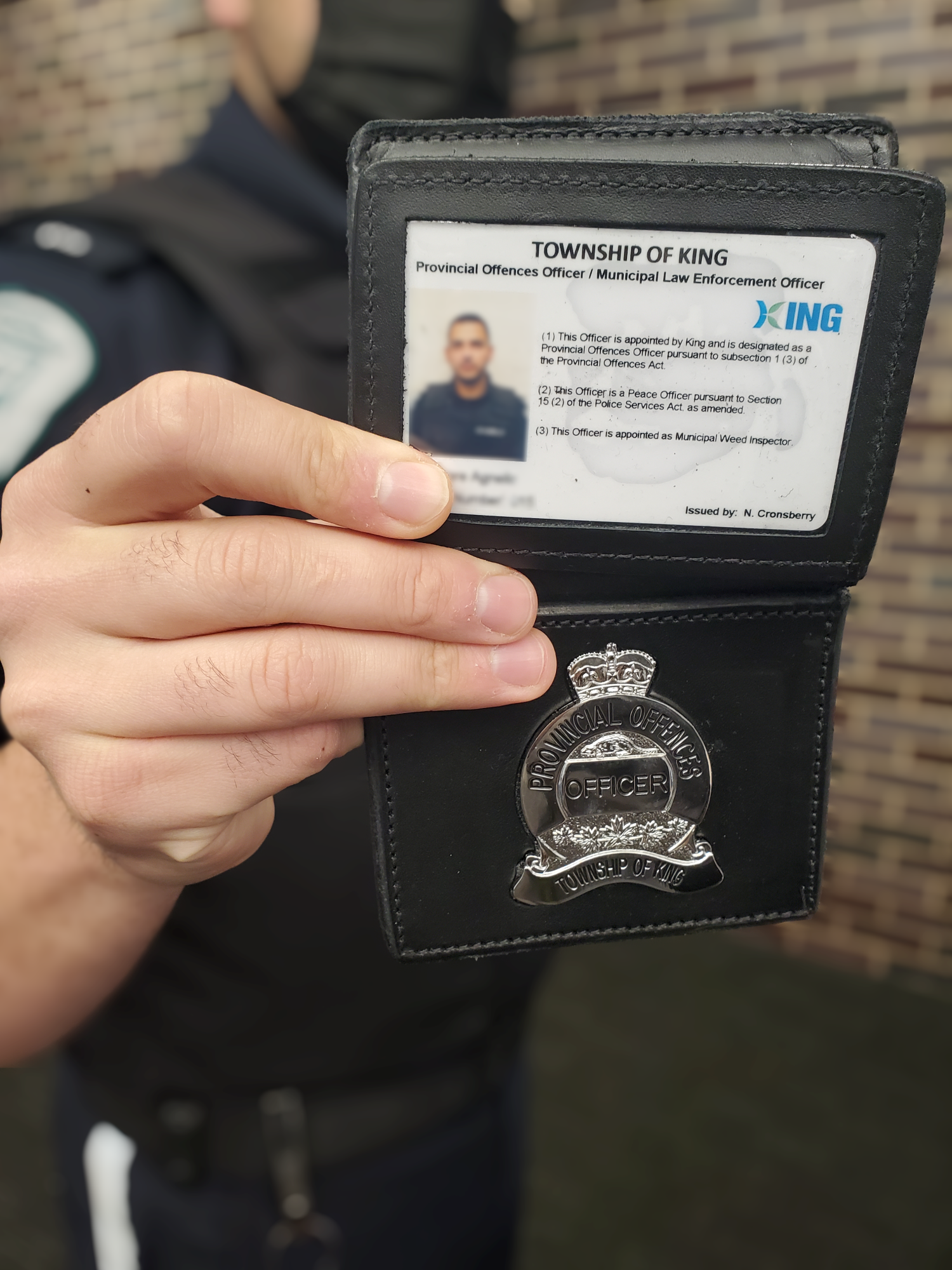 image of by-law enforcement officer holding up their badge