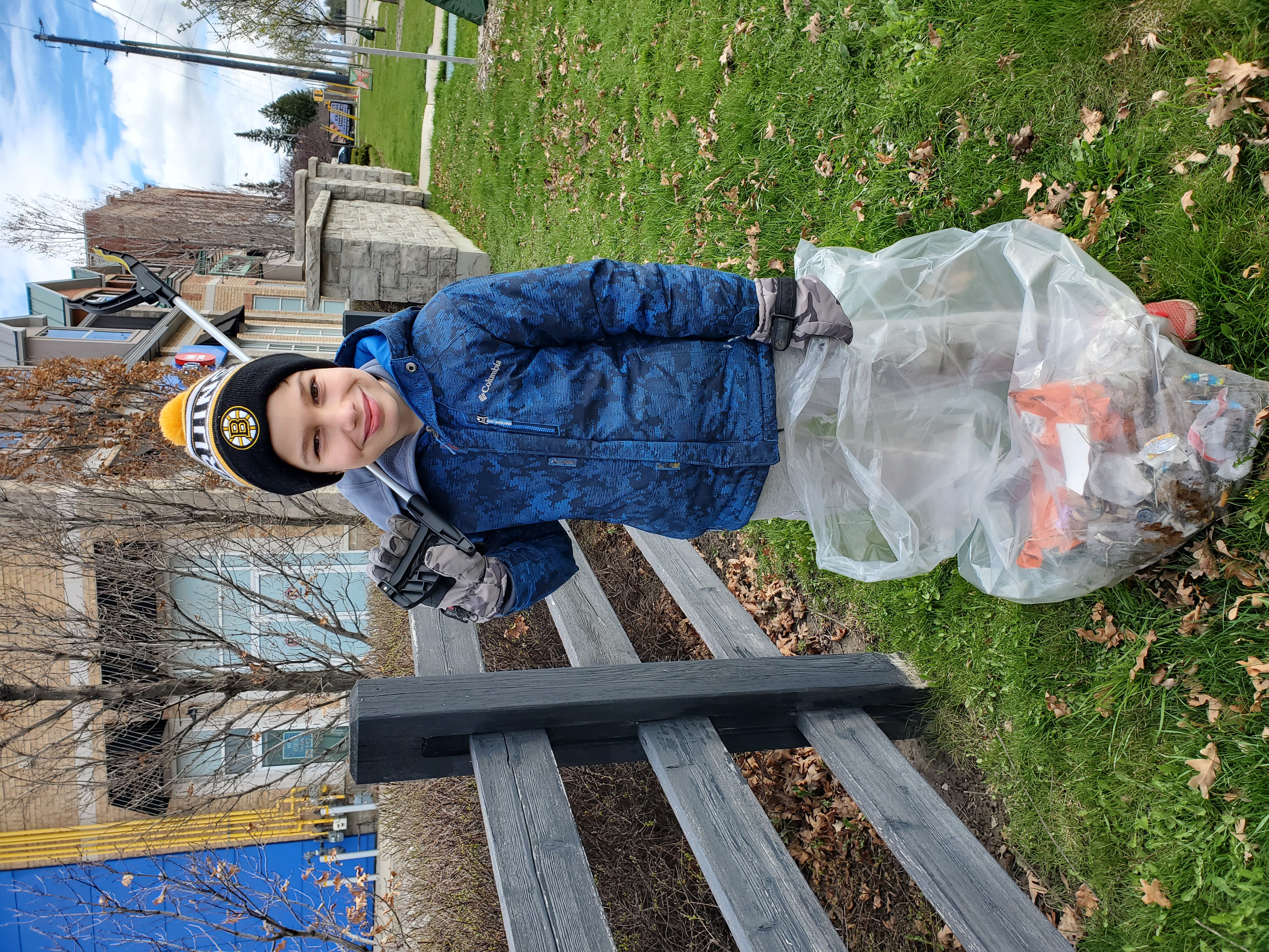 Child smiling, picking up litter during community clean up event