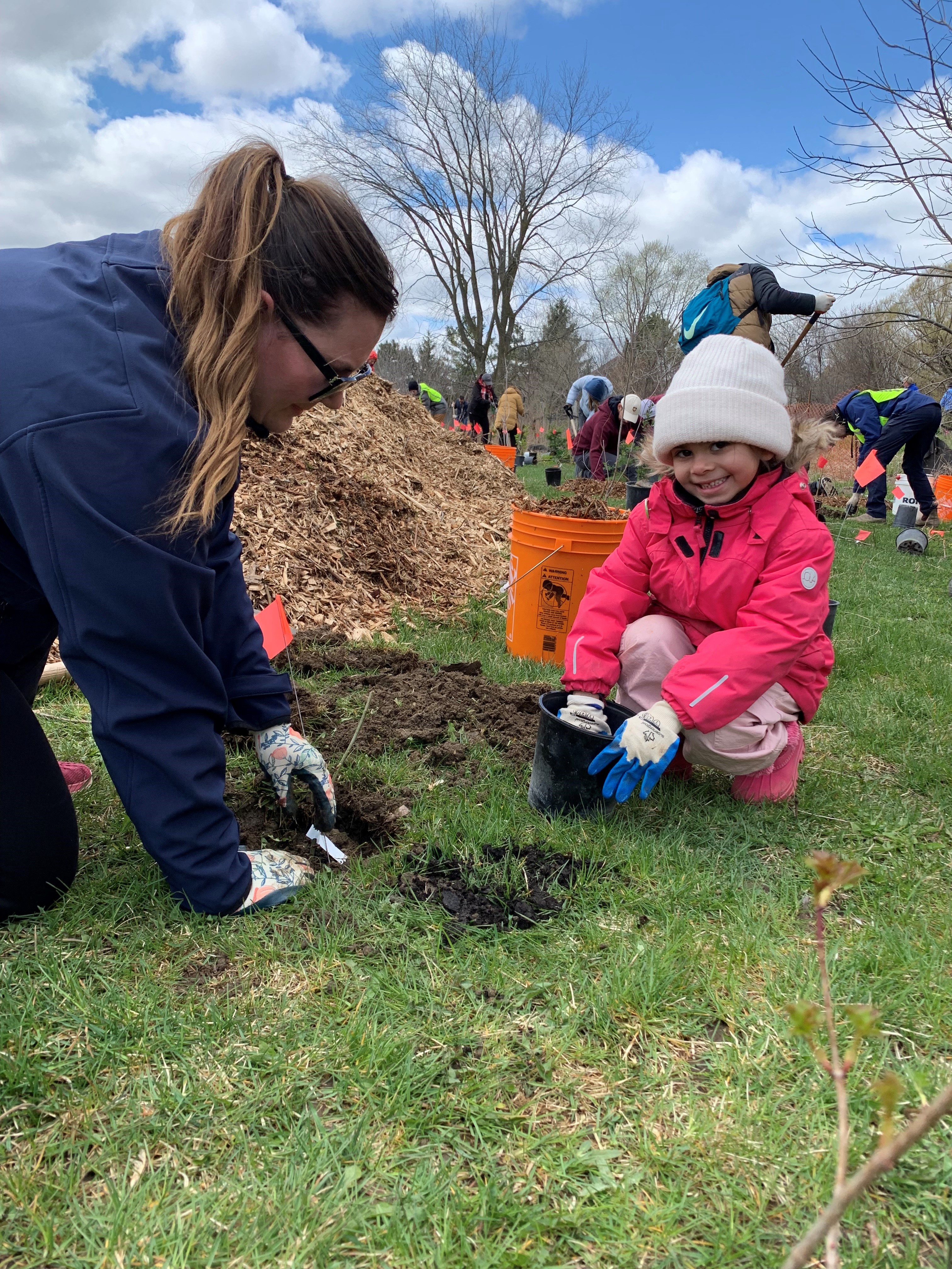 Child smiling planting tree with King Township staff