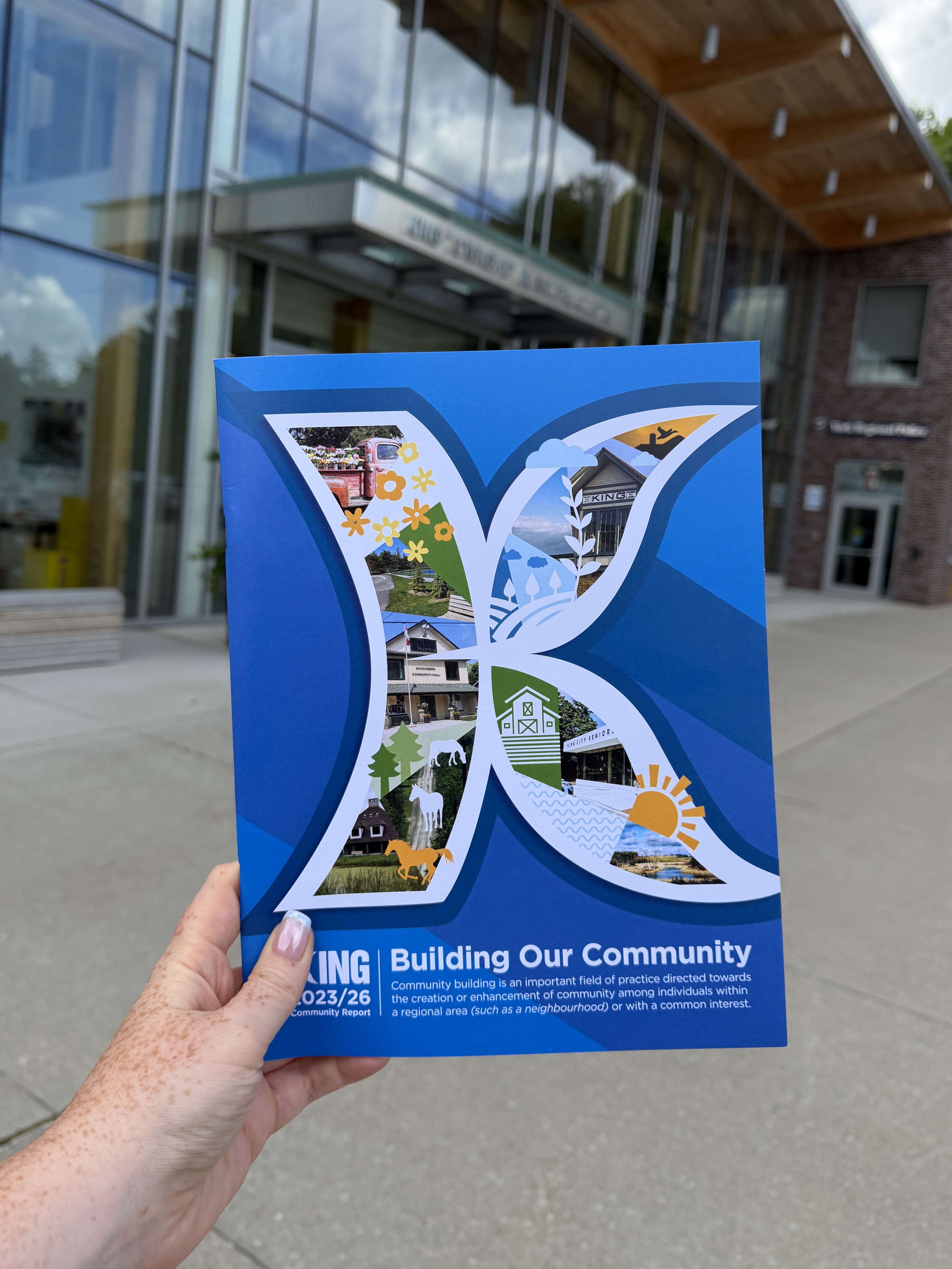 King Township's 2023-26 Community Report being held up on display in front of the King Township Municipal Centre