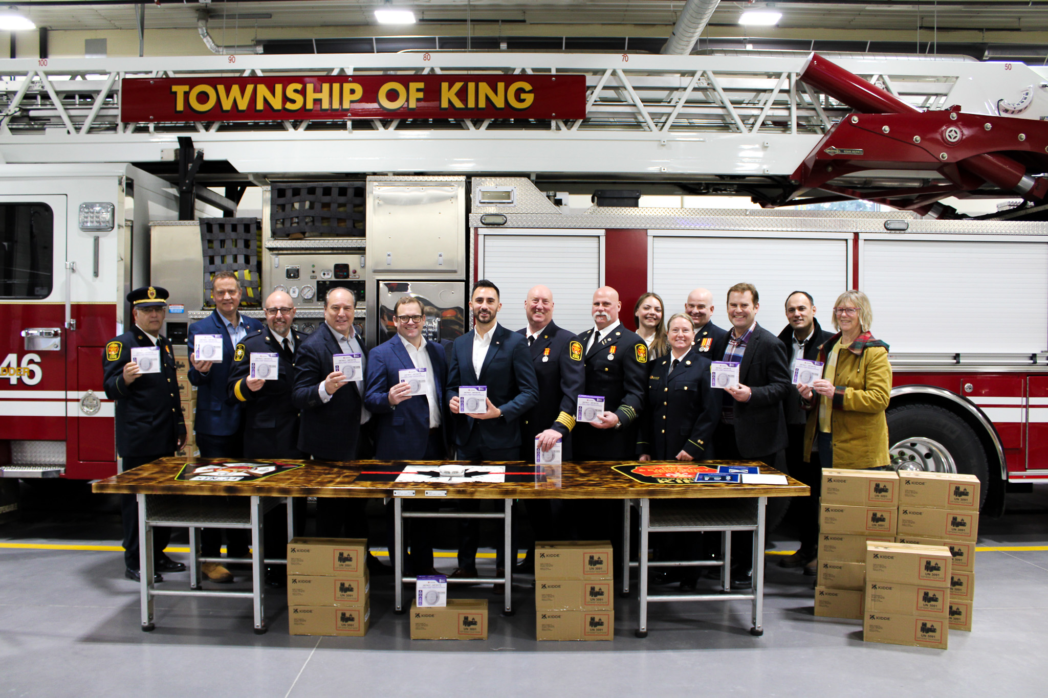 People gathered in front of a firetruck holding carbon monoxide alarms