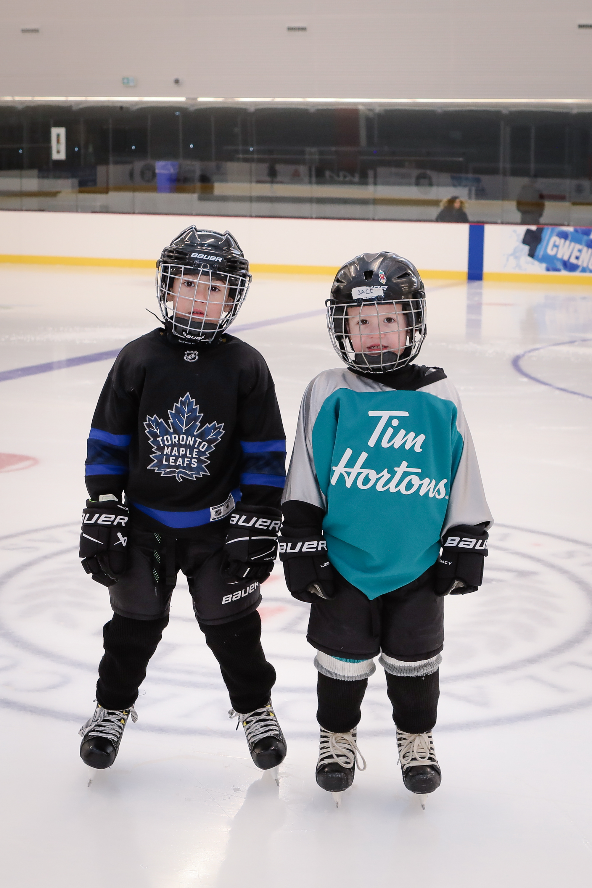 Two children wearing hockey equipment skating
