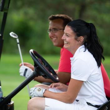 two people in a golf cart smiling