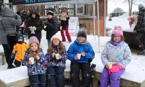 Kids sitting on a bench drinking hot chocolate