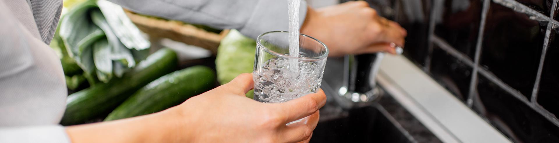 person filling water glass with tap water