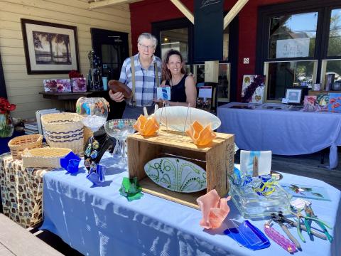image of artists from the Olde Mill Art Gallery & Shoppe with a table of local artwork on sale for sidewalkable saturday event