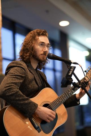 Person singing into microphone playing a guitar