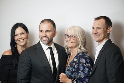 Group of people in formal attire smiling gathered in professional photobooth
