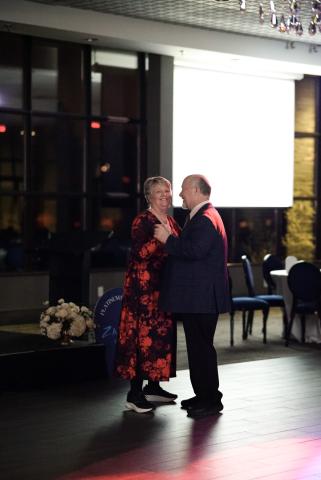 Two people dancing in formal attire with elegant backdrop