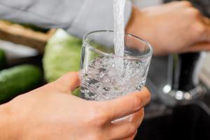 person filling water glass with tap water