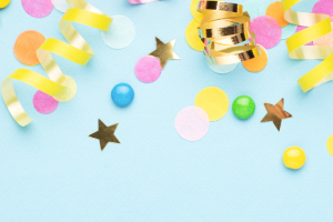 Banner image of multicolour confetti and ribbon on a light blue background.