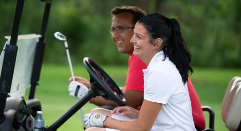 two people in a golf cart smiling